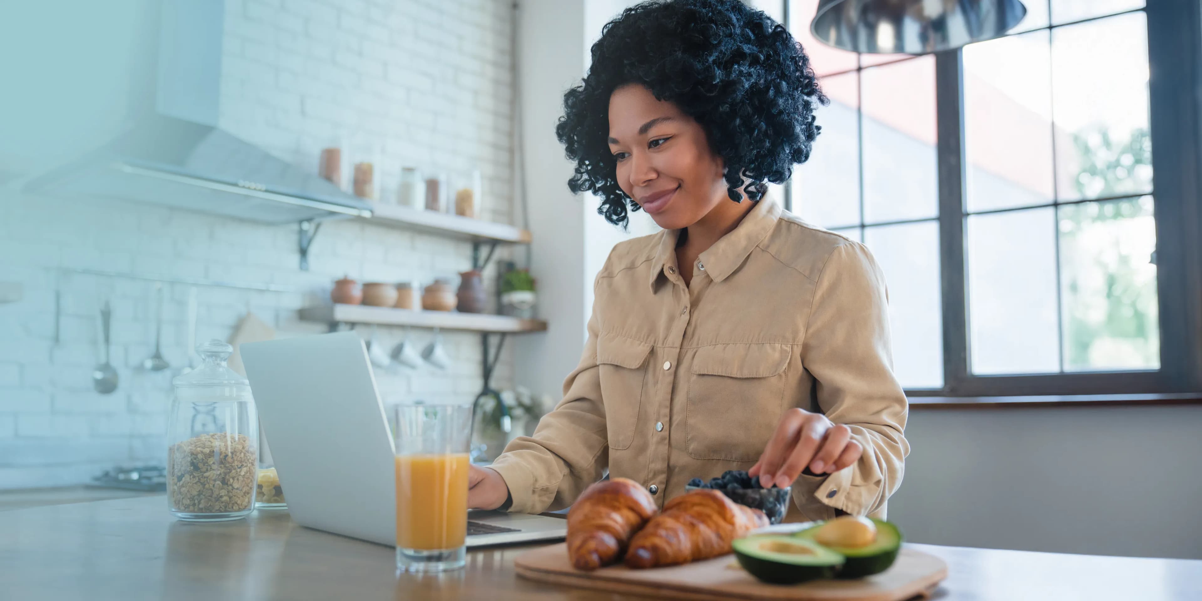 Woman eating breakfast and using a laptop